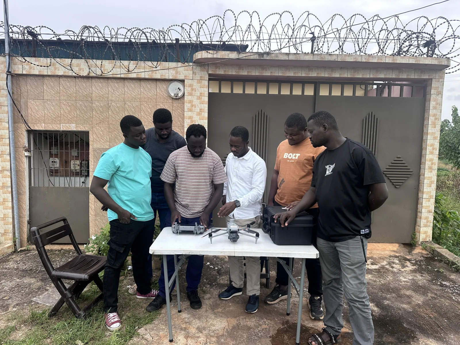 Six stagiaires réunis autour d'un drone et de sa mallette, à l'entrée du centre de Dabou